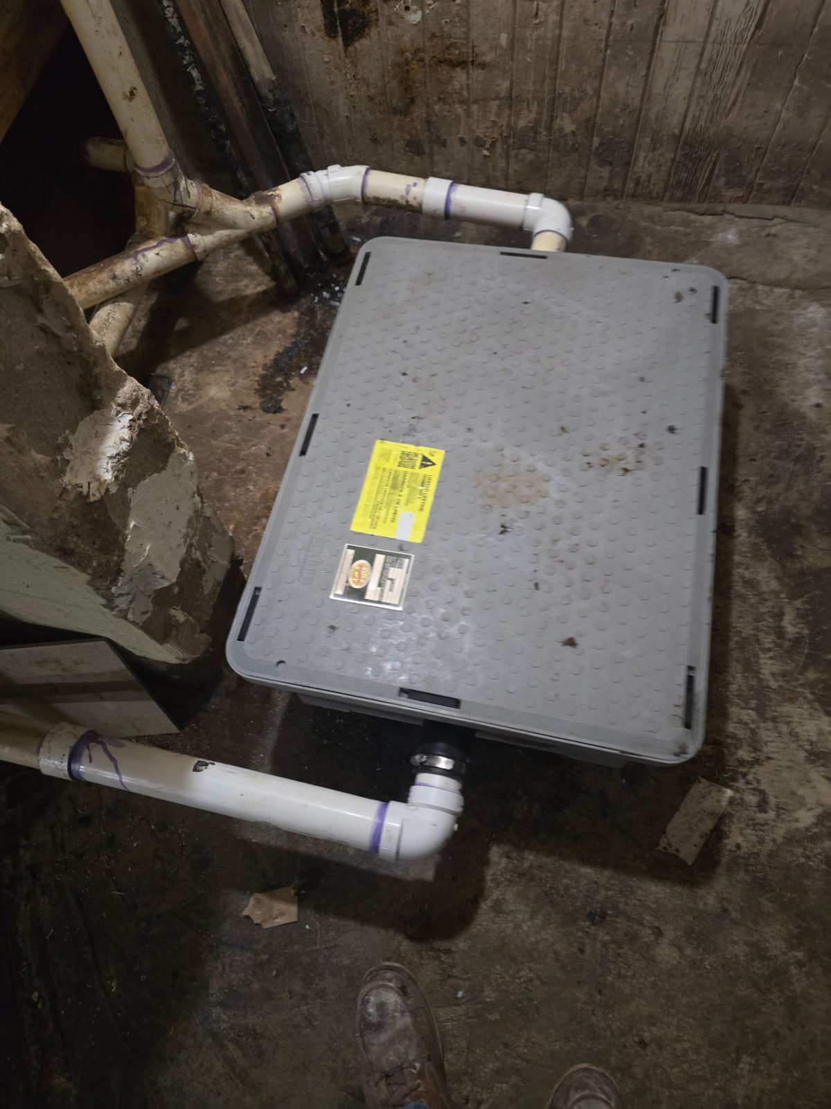 New PVC drain lines and sealed sewage ejector basin installed under a house
