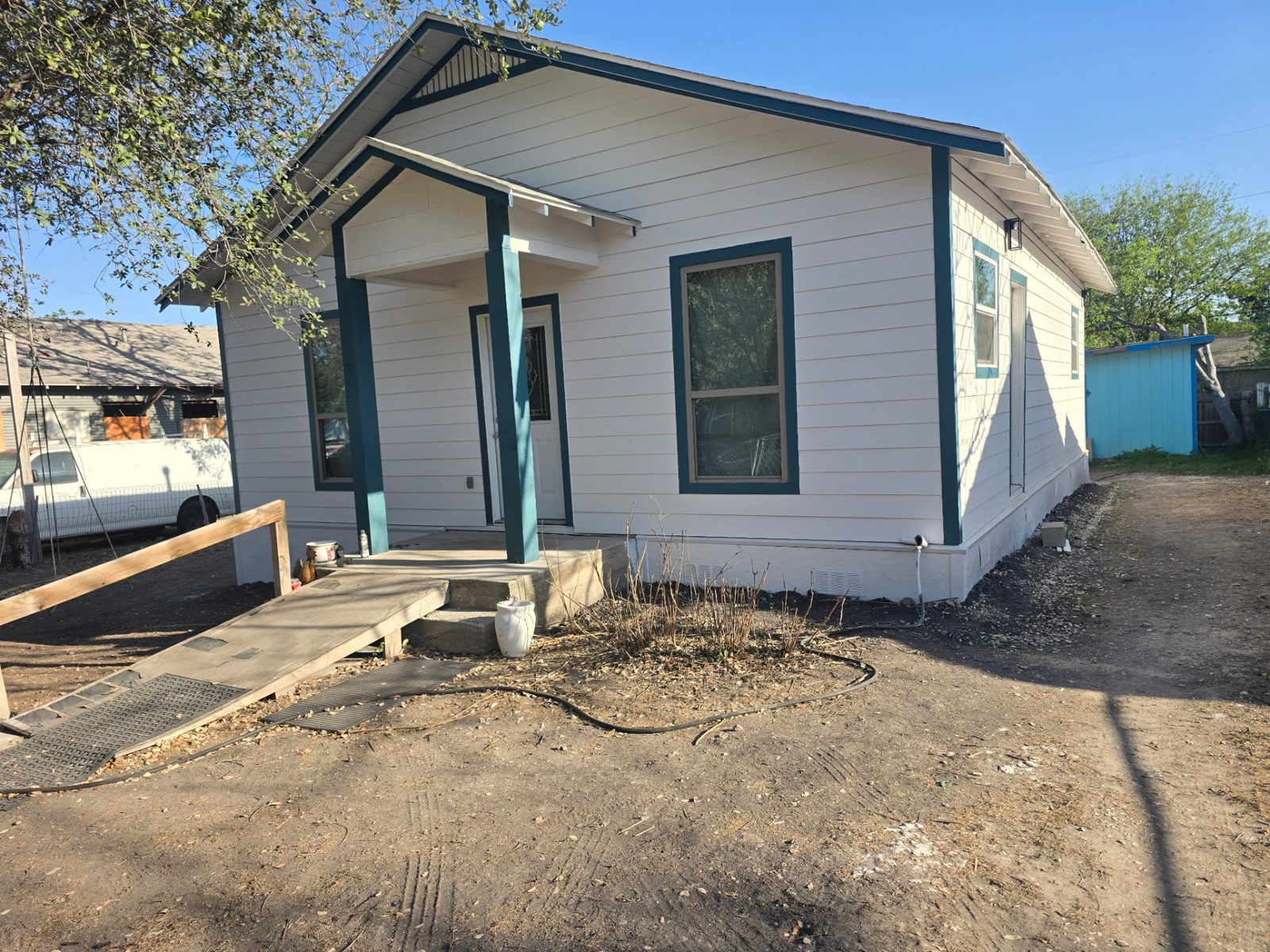 Remodeled white home with teal trim, new siding, porch and wheelchair ramp