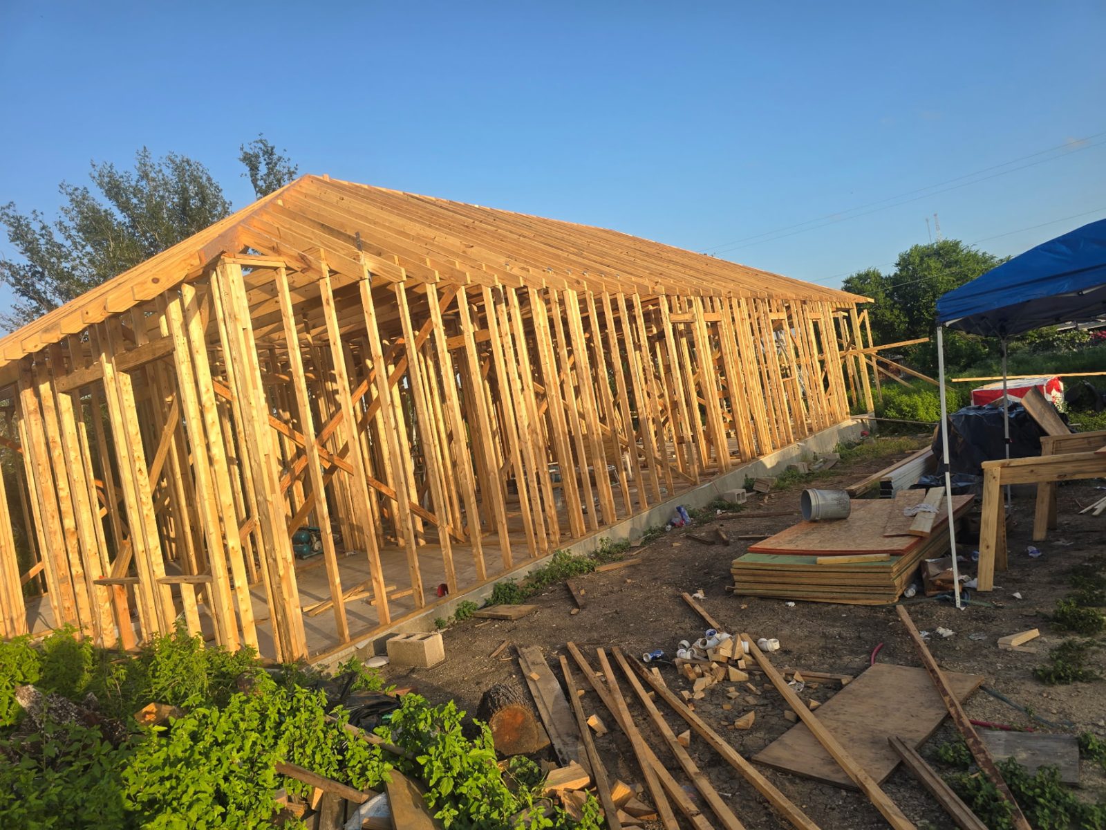 Completed wood framing and roof rafters of a new house at sunset